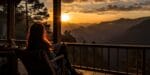 female traveler alone on porch in the mountains watching sun set